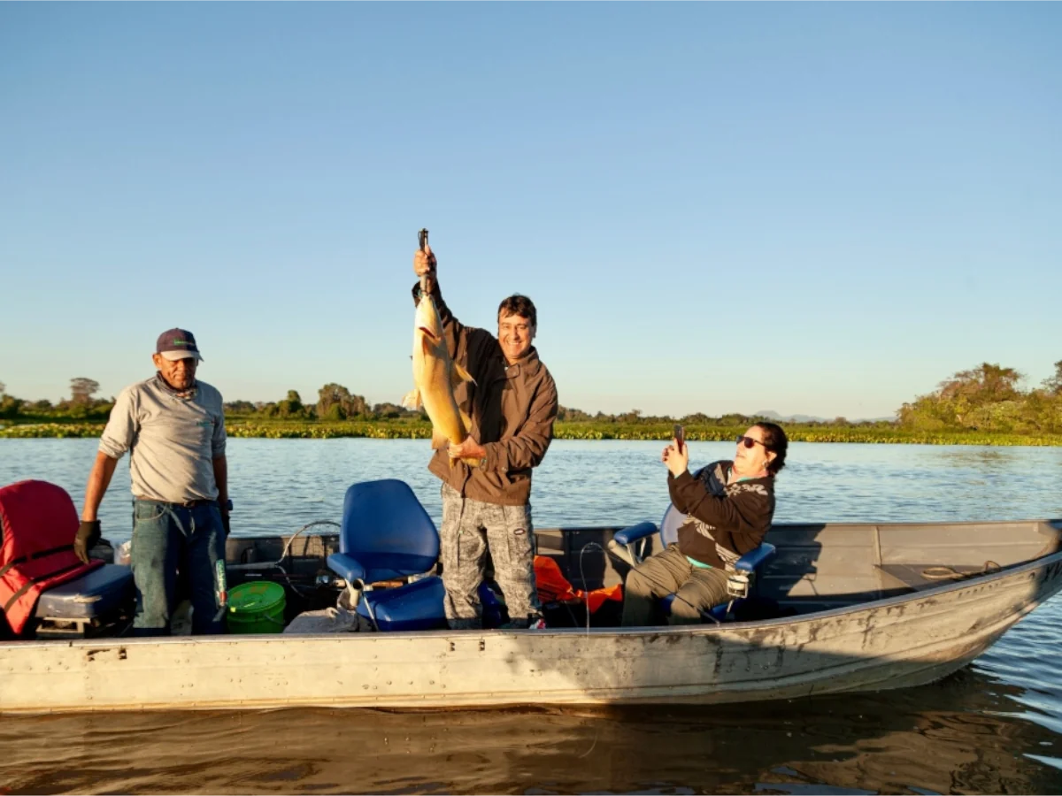 Pescador com pintado pescado no Rio Paraguai ao entardecer